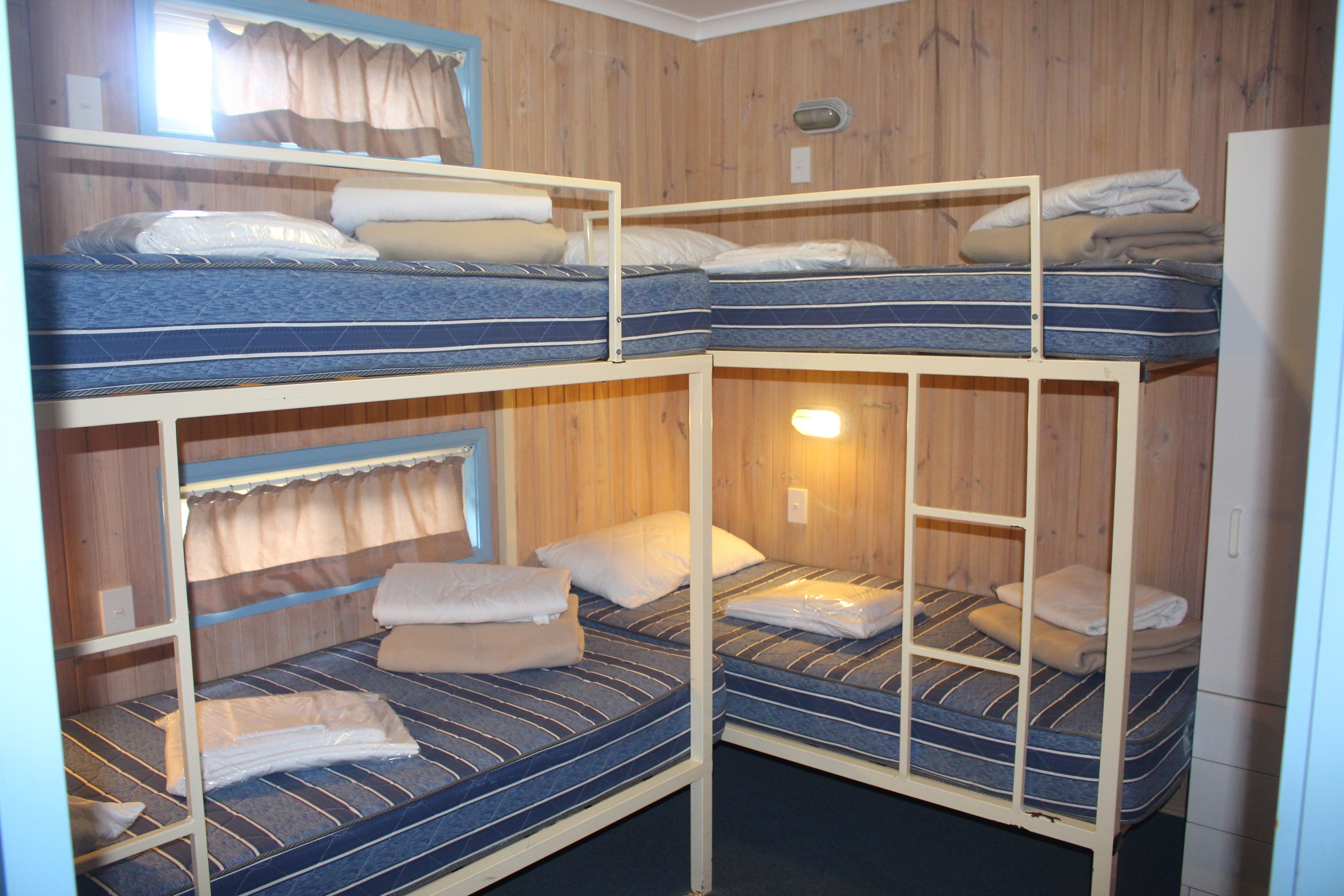 Habitación con literas de madera y una cama individual en la parte inferior.