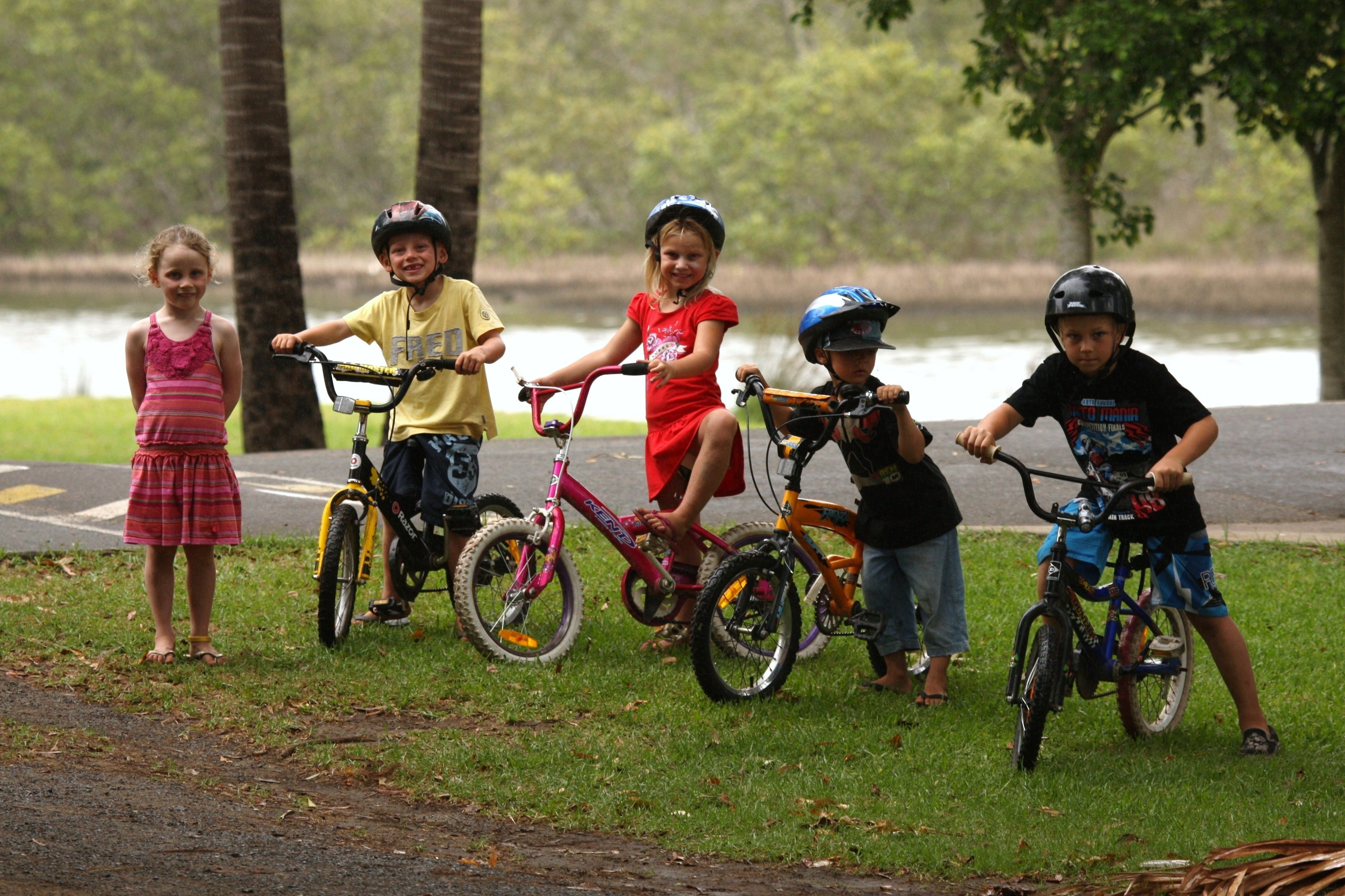 Un grupo de niños con bicicletas cerca de un cuerpo de agua, posiblemente un parque o lago.