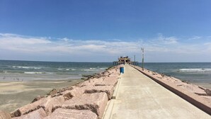 Un muelle que se adentra en el océano con un edificio al final.