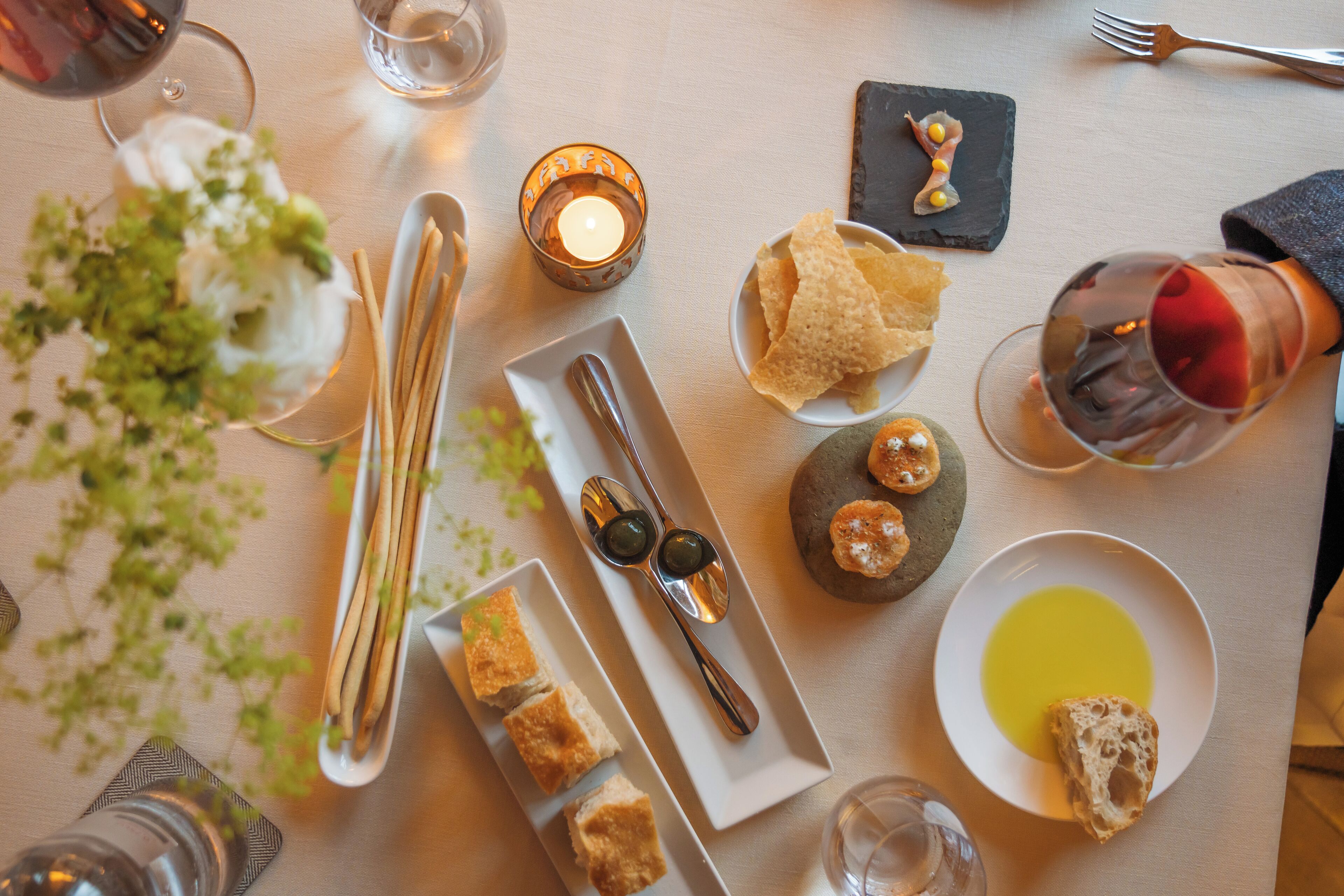 Una tavola imbandita per un pasto, con diversi piatti, bicchieri di vino e una candela.