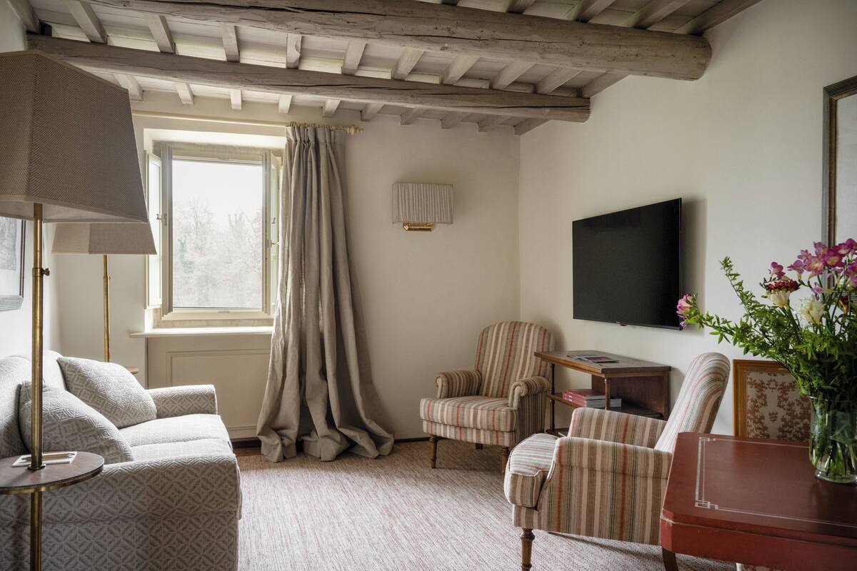 Un salón acogedor con un sofá, sillones, un televisor y una mesa de madera.