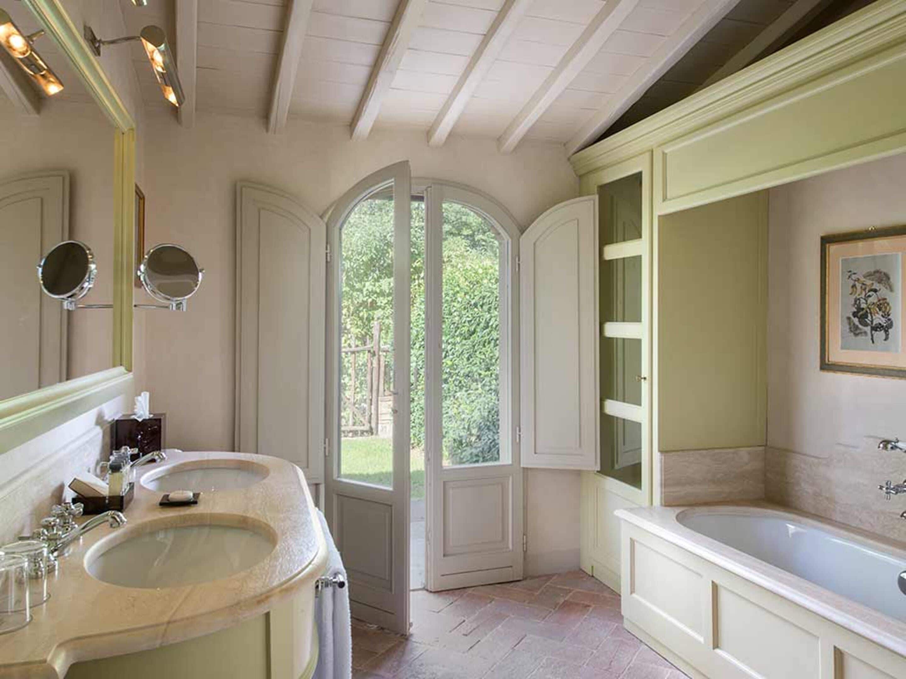 A bathroom with two sinks, a bathtub, and a large mirror.