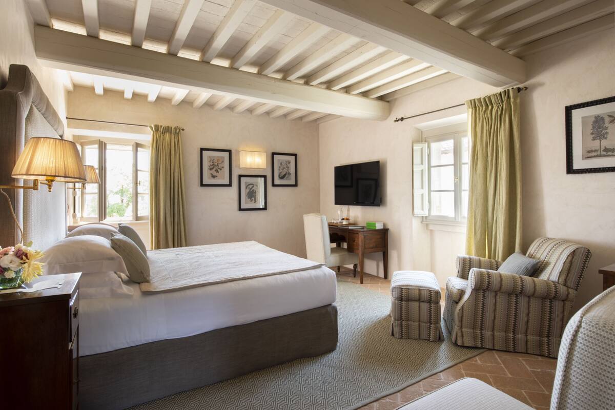 A bedroom with a bed, a desk, a chair, and a television.