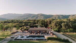 Un hotel con piscina, asientos exteriores y vistas a las colinas circundantes.