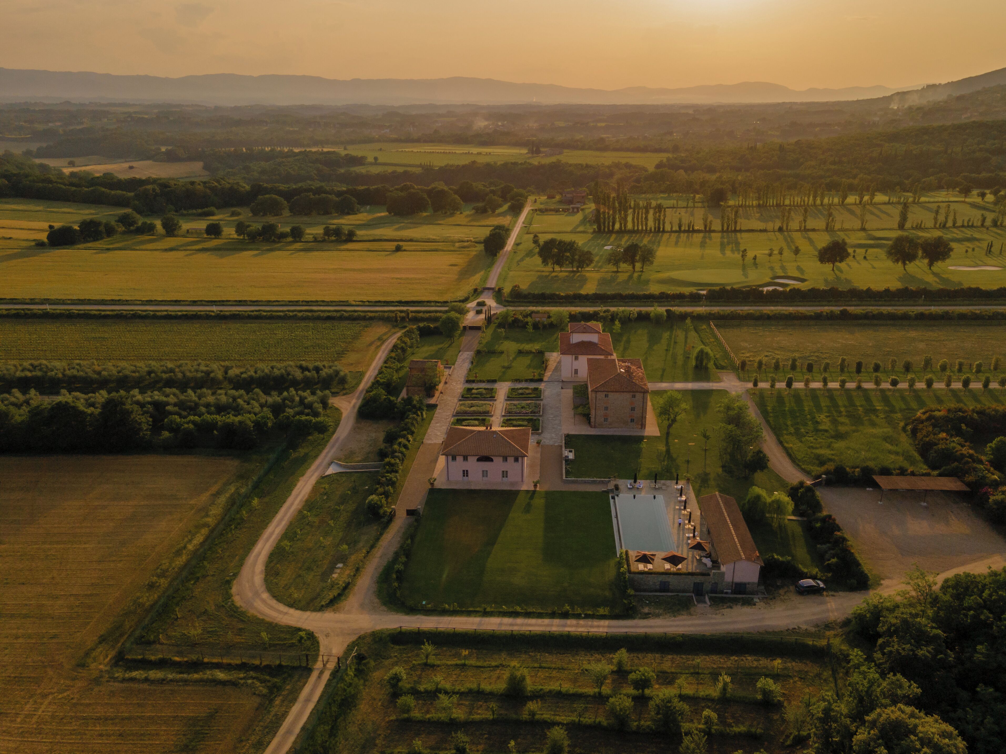 An aerial view of a rural estate with a main building, several smaller structures, and extensive agricultural fields.