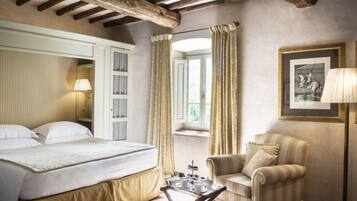 A hotel room with a bed, a chair, a tray with breakfast items, and a framed picture on the wall.