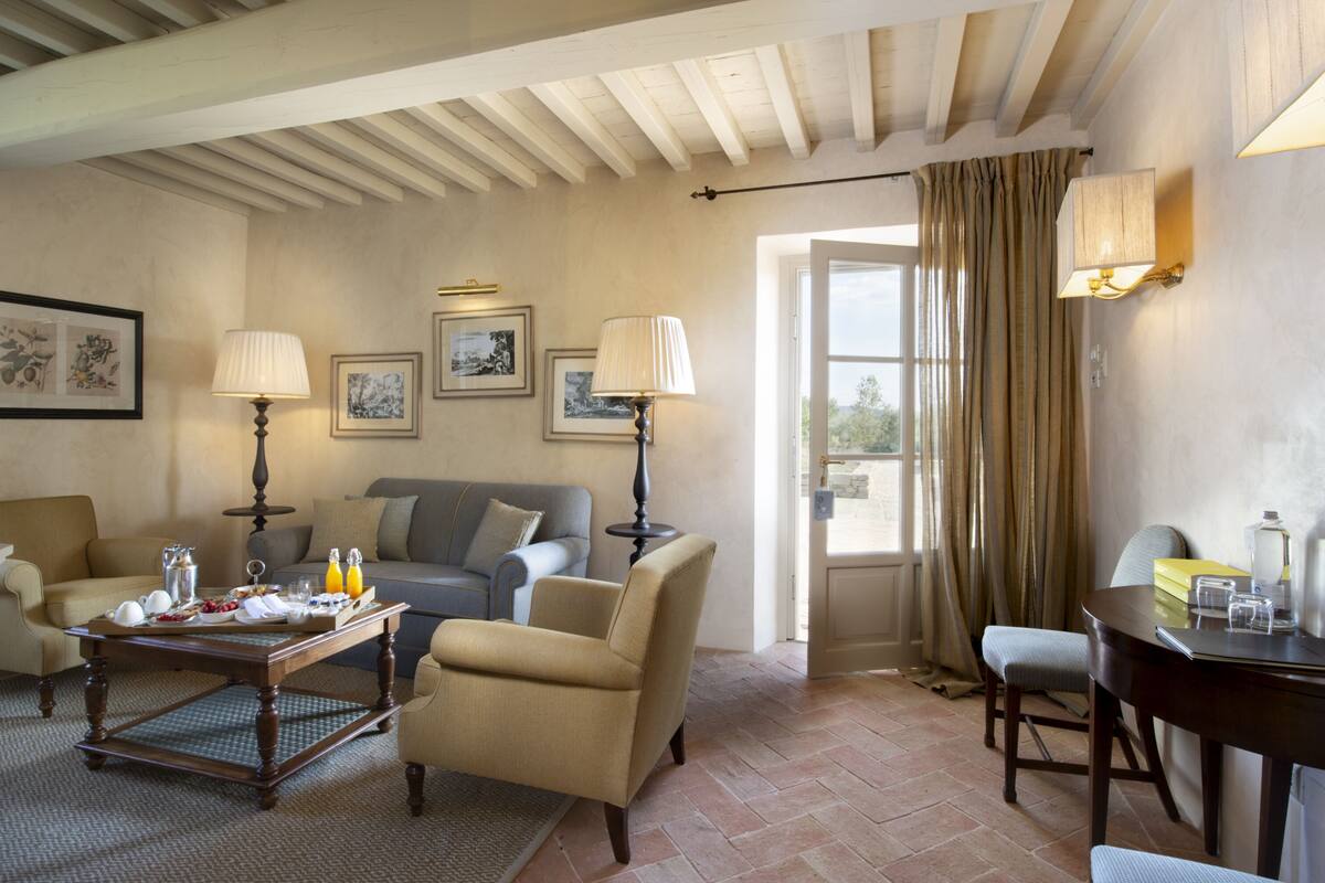 Una sala de estar acogedora con un sofá, sillones, una mesa de centro y una mesa de comedor con una lámpara.