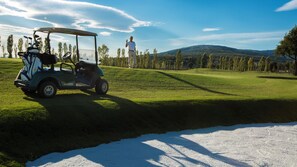 A golf cart on a green with a person standing in the background.