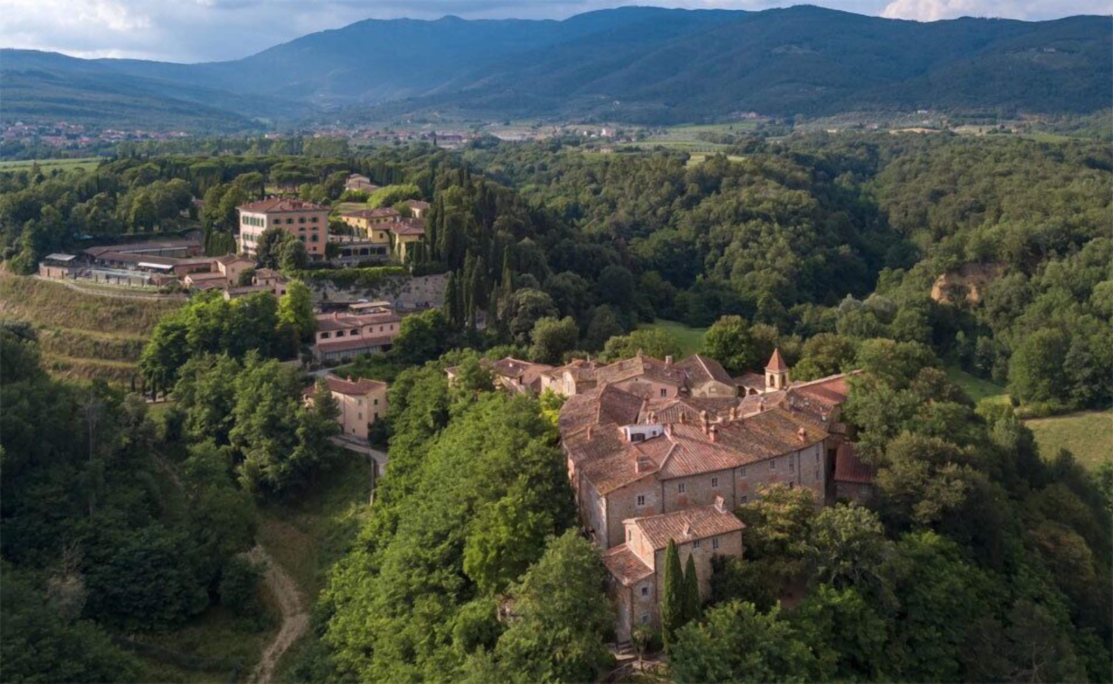 A rural village with traditional stone buildings surrounded by lush greenery and hills in the background.