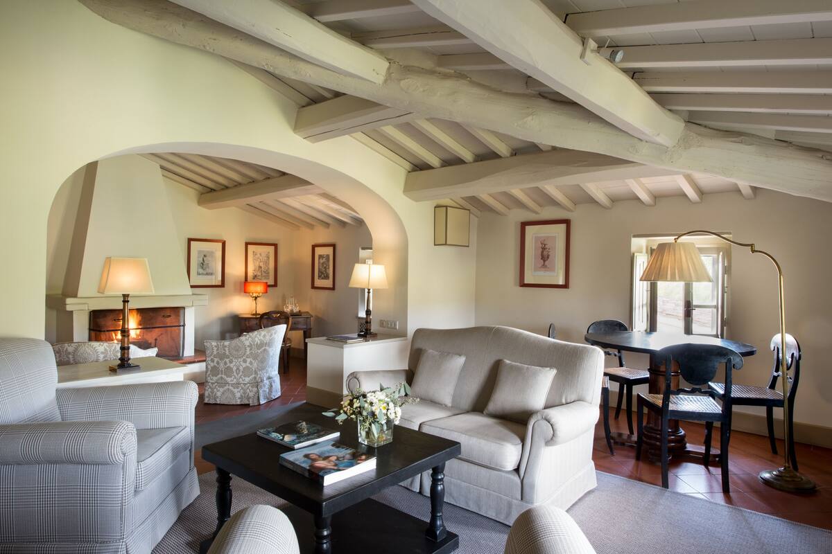 A cozy living room with a fireplace, comfortable seating, and a dining area.