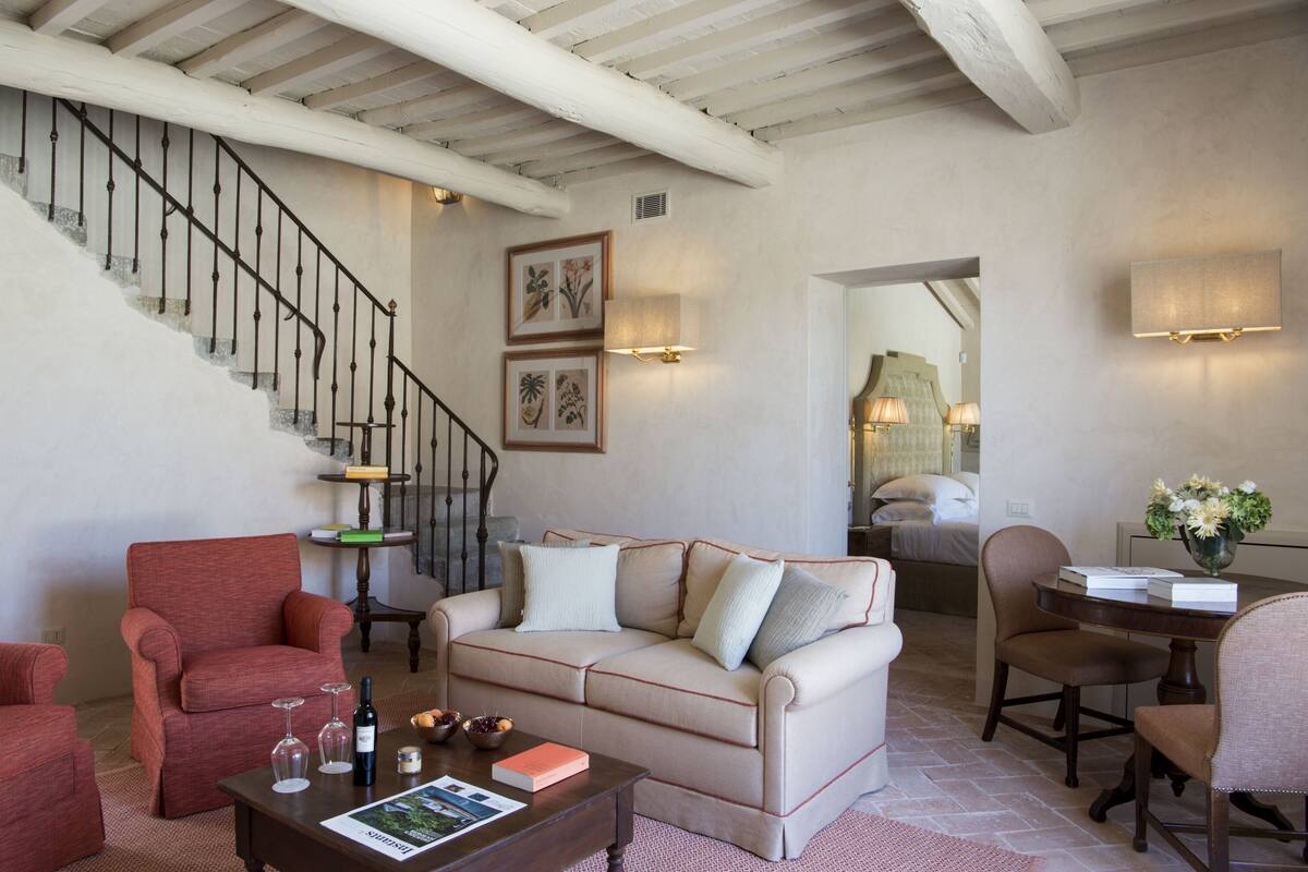 A living room with a staircase, a sofa, a coffee table, and a dining area.