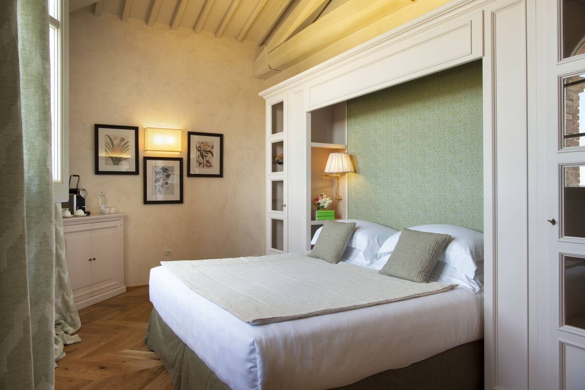 Un dormitorio ordenado con cama, mesitas de noche y lámparas de pared.