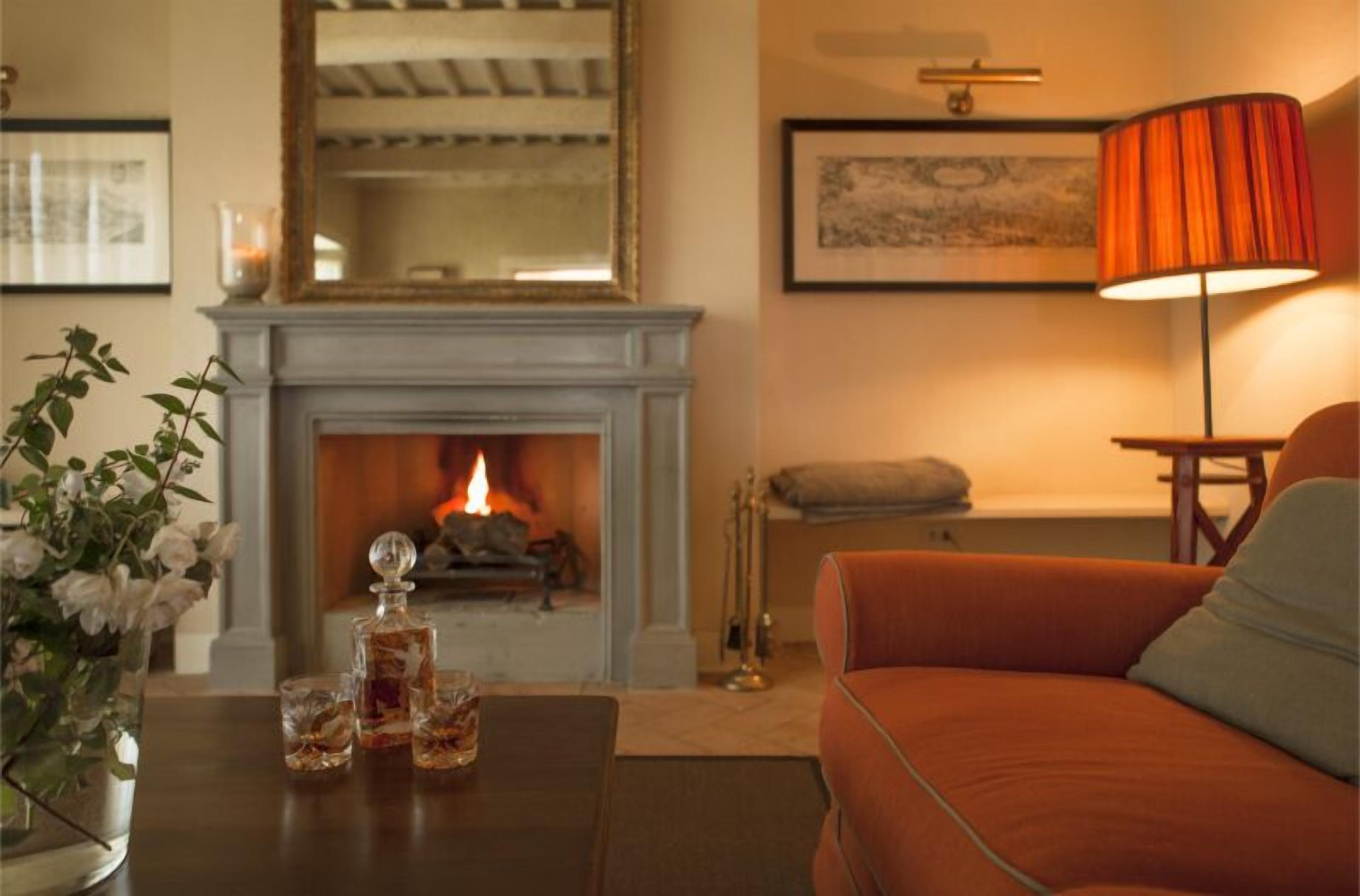 Ein gemütliches Wohnzimmer mit Kamin, einer Couch, einem Couchtisch mit Getränken und einer Lampe.