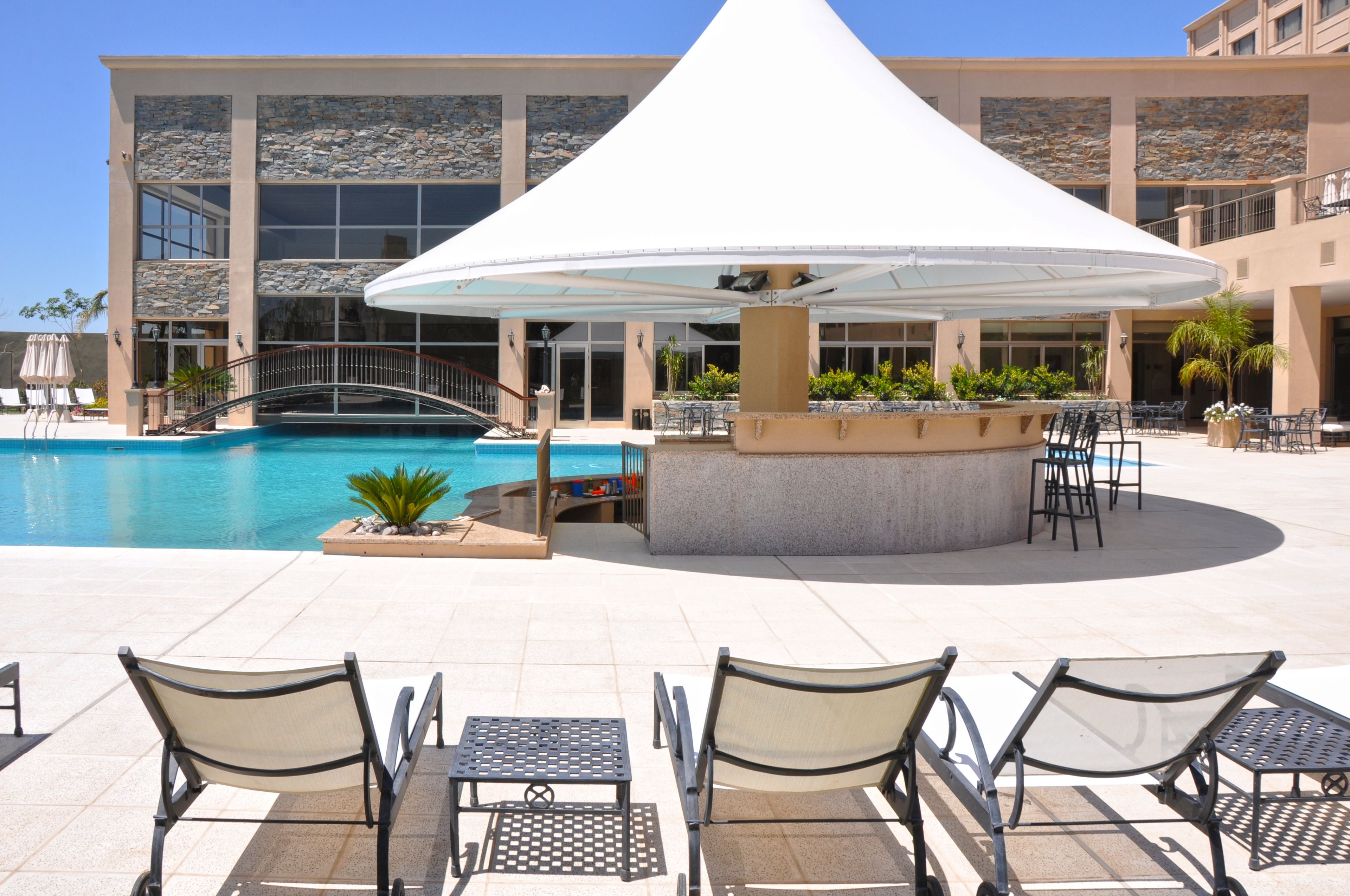 A pool area with lounge chairs and a covered seating area.