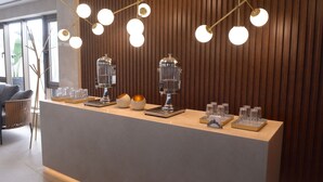 Zona de recepción con un diseño moderno, que incluye una pared de madera, un mostrador con cristalería y una lámpara de diseño único.