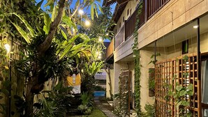A courtyard with a stone pathway, lush greenery, and hanging lights. - Villa Puriartha Ubud (Ubud)