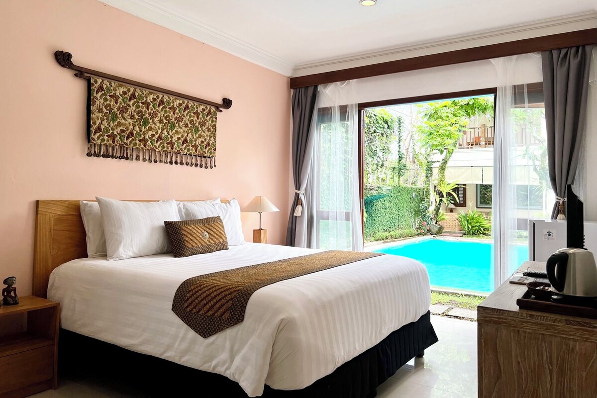 Habitación de hotel con cama, mesita de noche, televisor y vista a una piscina.