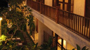 A two-story building with wooden balconies and a garden area. - Villa Puriartha Ubud (Ubud)