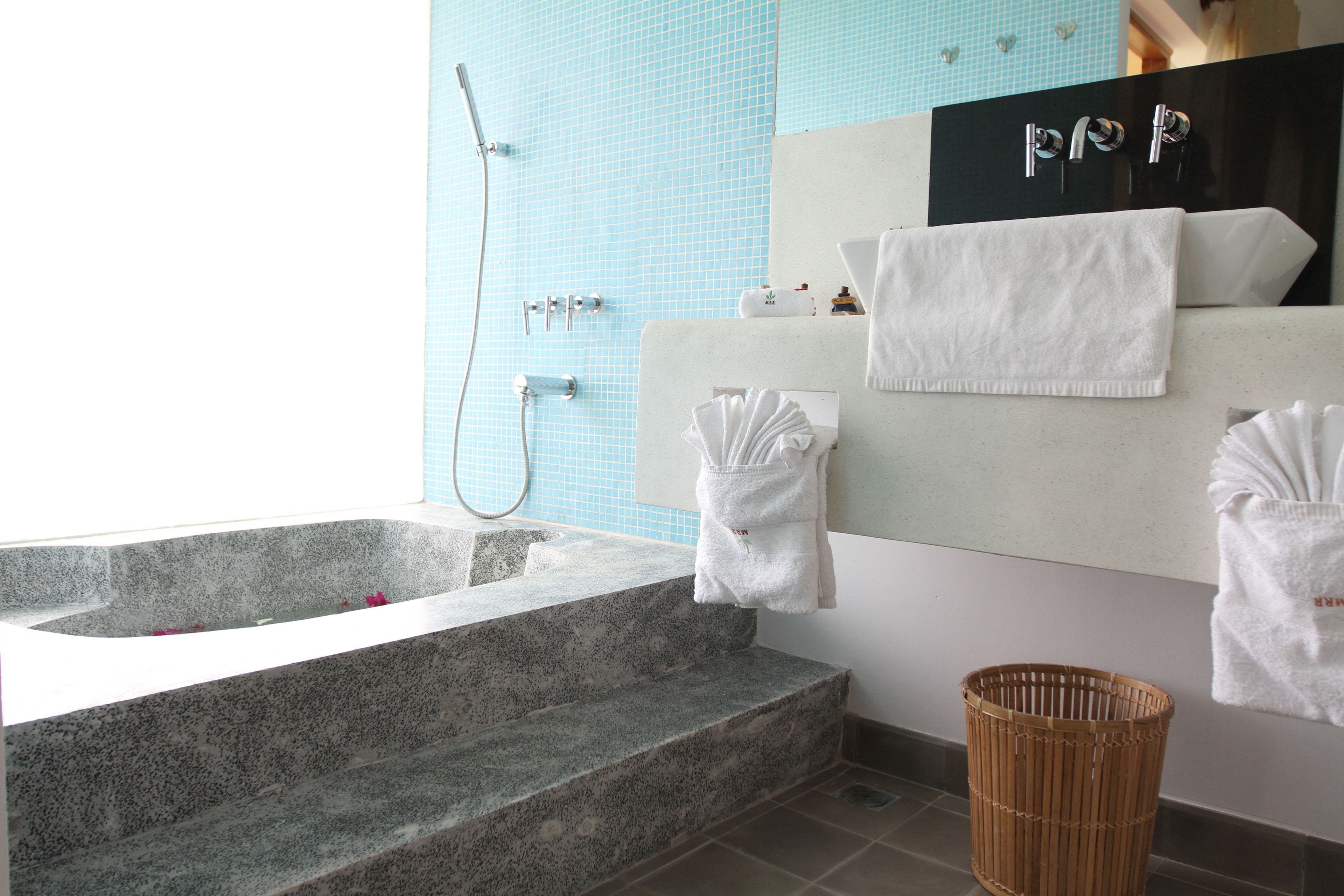 A modern bathroom with a stone bathtub, a shower, and a large mirror.