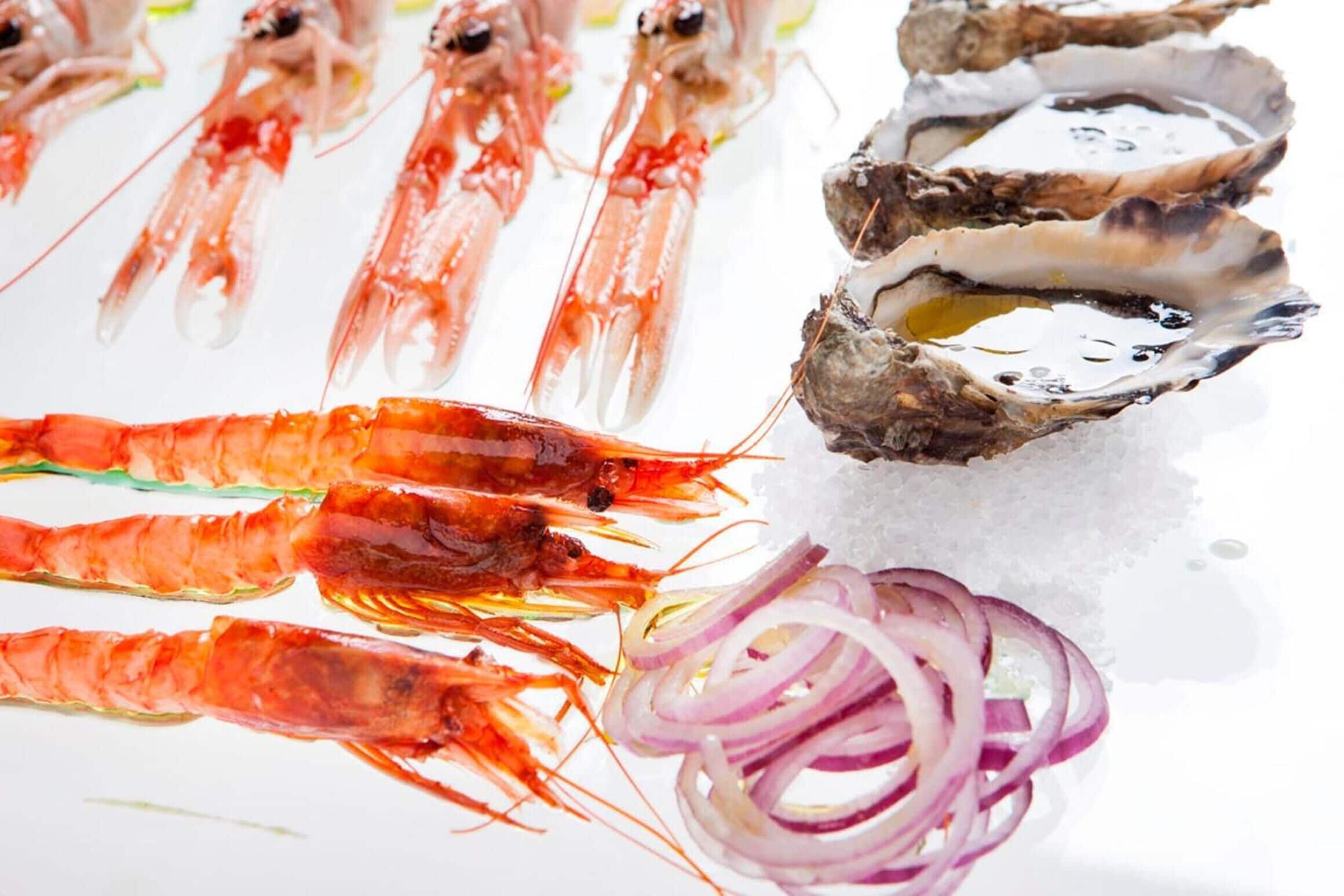 A variety of seafood including prawns and oysters on ice.
