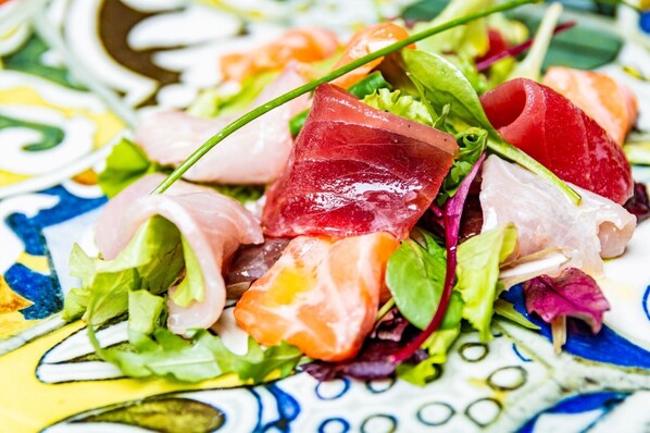 A colorful salad with various greens and slices of meat.