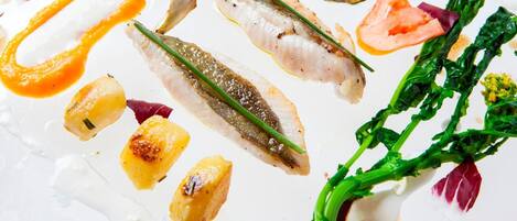 A white plate with various food items including fish, vegetables, and sauces.