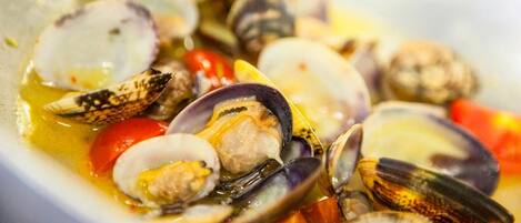 A bowl of seafood with clams and tomatoes.