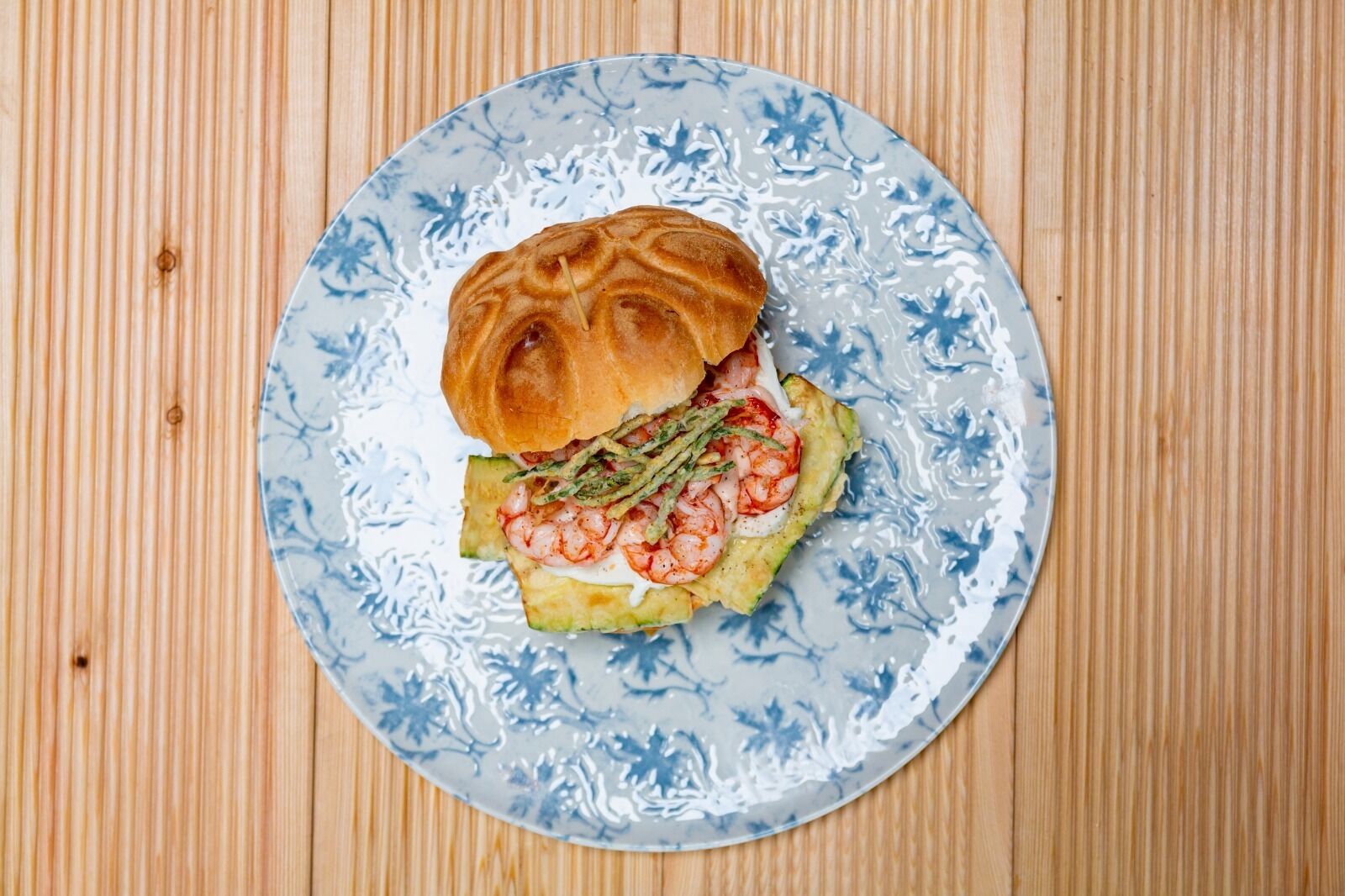 Un sandwich servi sur une assiette ornée d’un motif floral bleu.