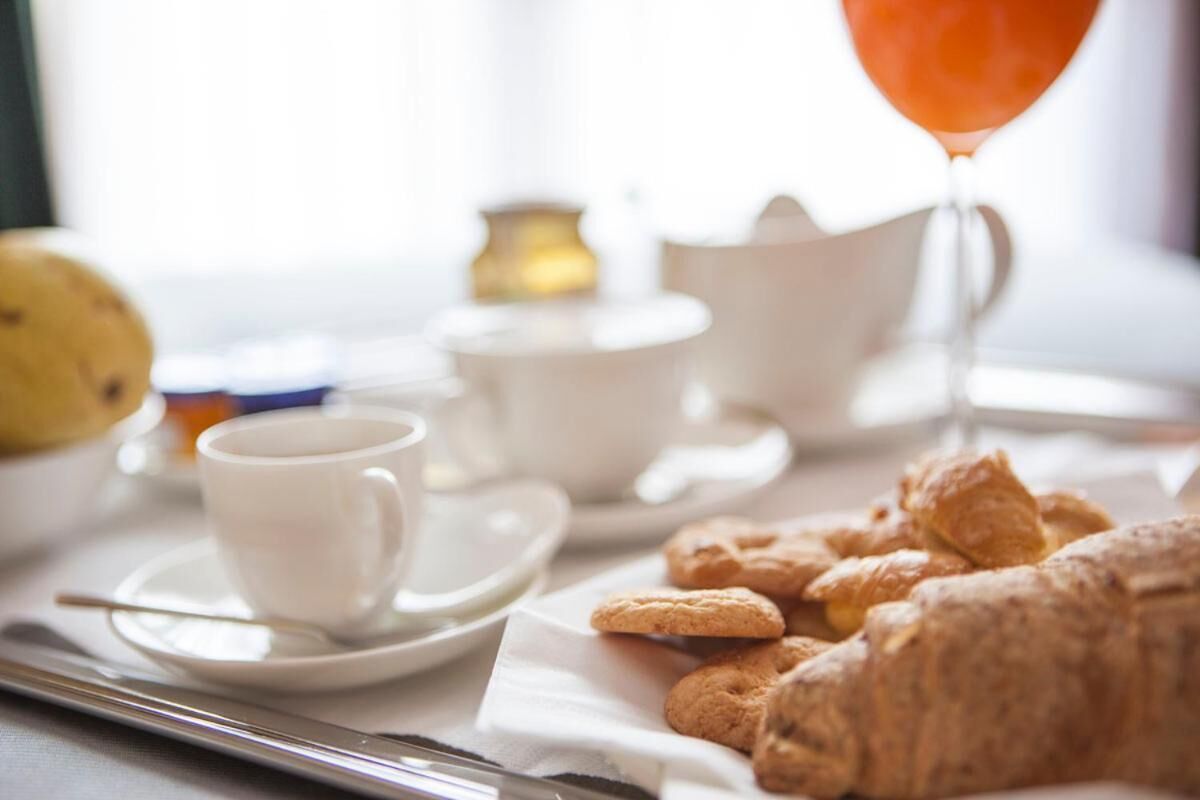 Una colazione con dolci, una tazza di caffè e un bicchiere di succo d'arancia su un tavolo.