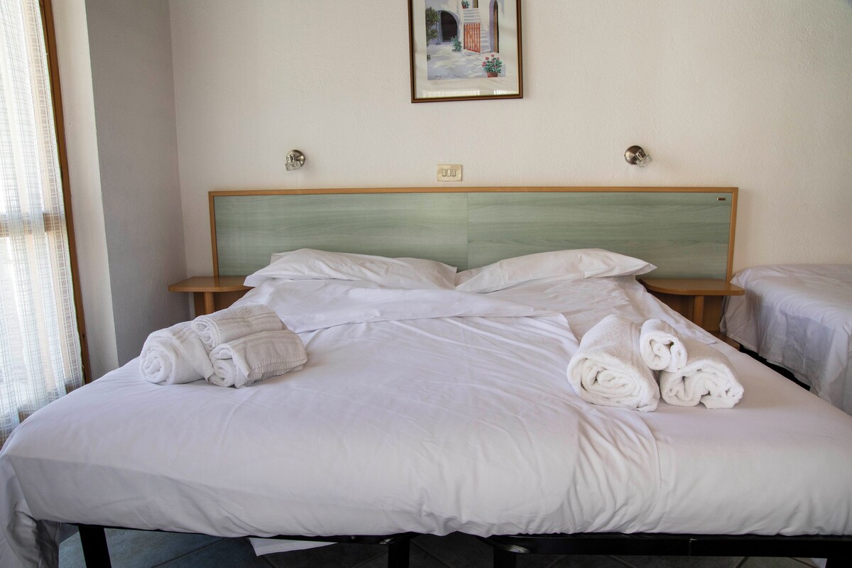 Una habitación de hotel con una cama, dos mesitas de noche y un cuadro en la pared.