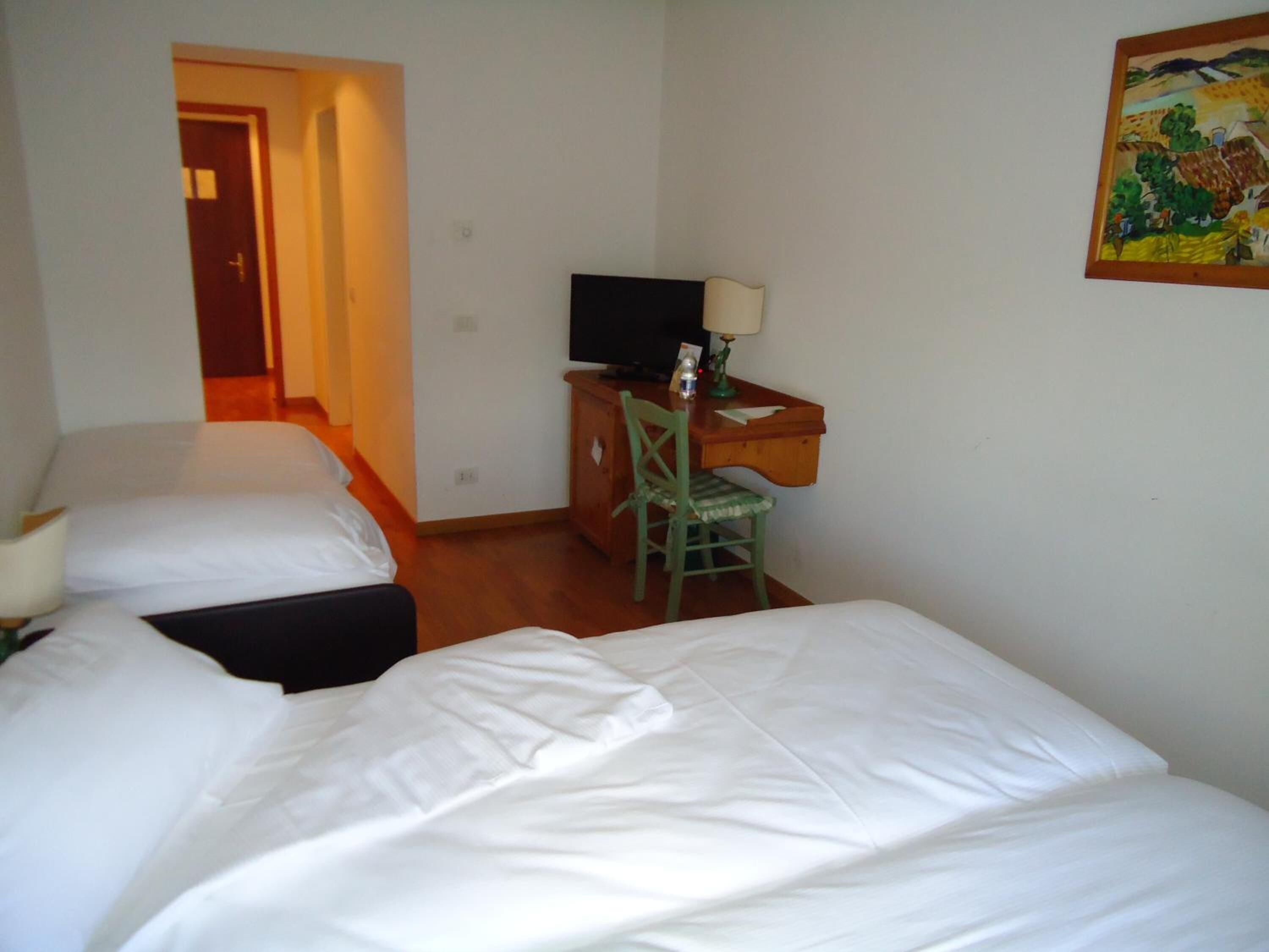 A hotel room with two beds, a desk with a television, and a chair.