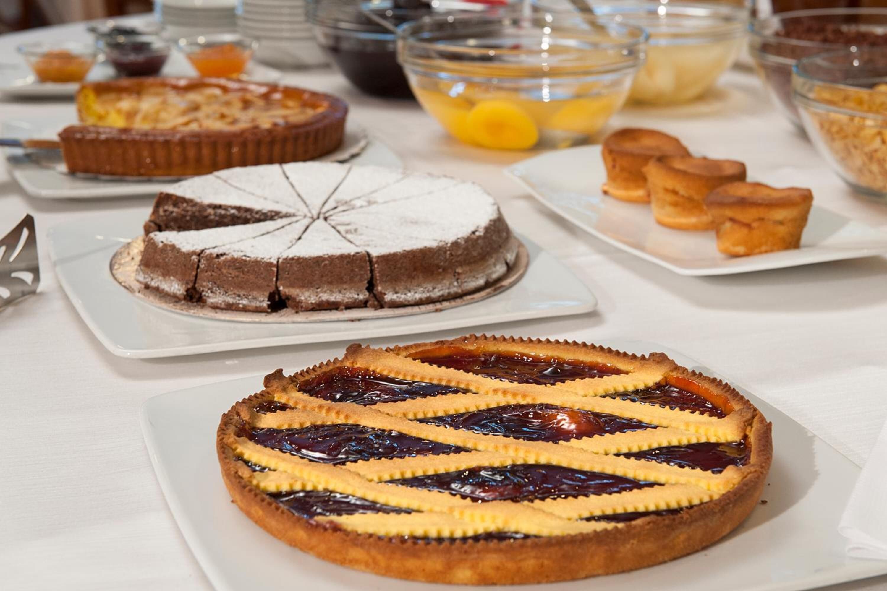 Verschiedene Desserts stehen auf einem Buffet, darunter ein Schokoladenkuchen, ein Kirschtorte und einige kleine Gebäckstücke.