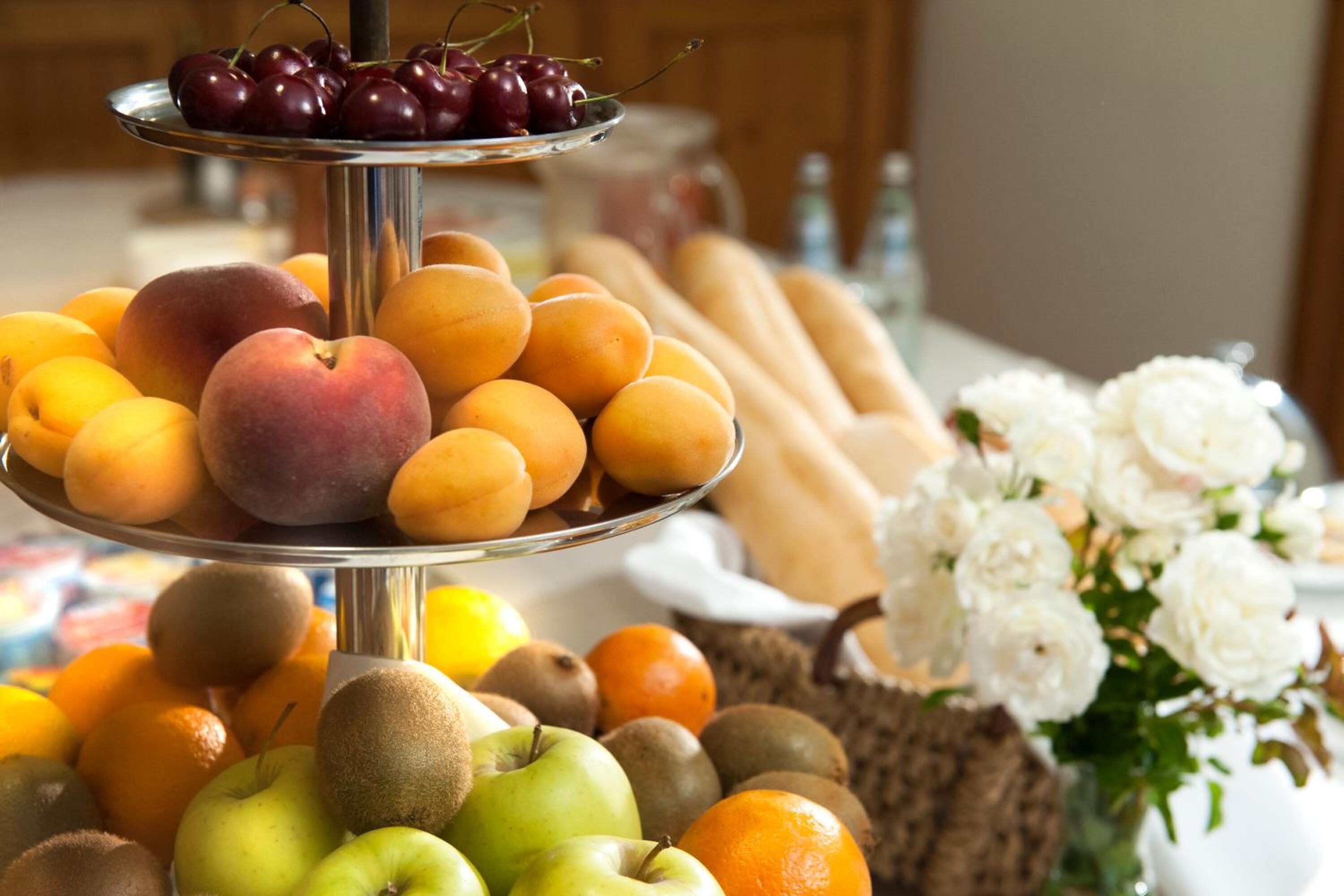 A fruit and flower display with peaches, cherries, apples, and flowers.