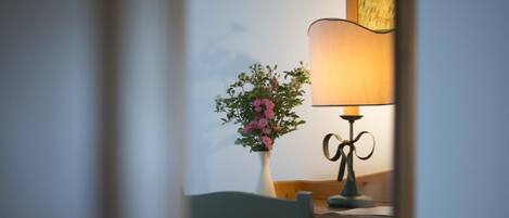 A room with a wooden desk, a vase with flowers, and a lamp.