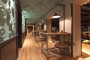 A bar area with wooden flooring, metal bar stools, and pendant lighting. - Relais Picaron (San Daniele del Friuli)