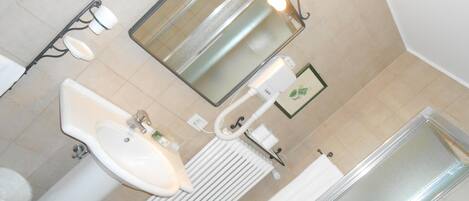 A bathroom with a sink, mirror, toilet, and shower.