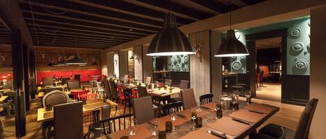 Un restaurante con varias zonas de comedor, mesas y sillas de madera.
