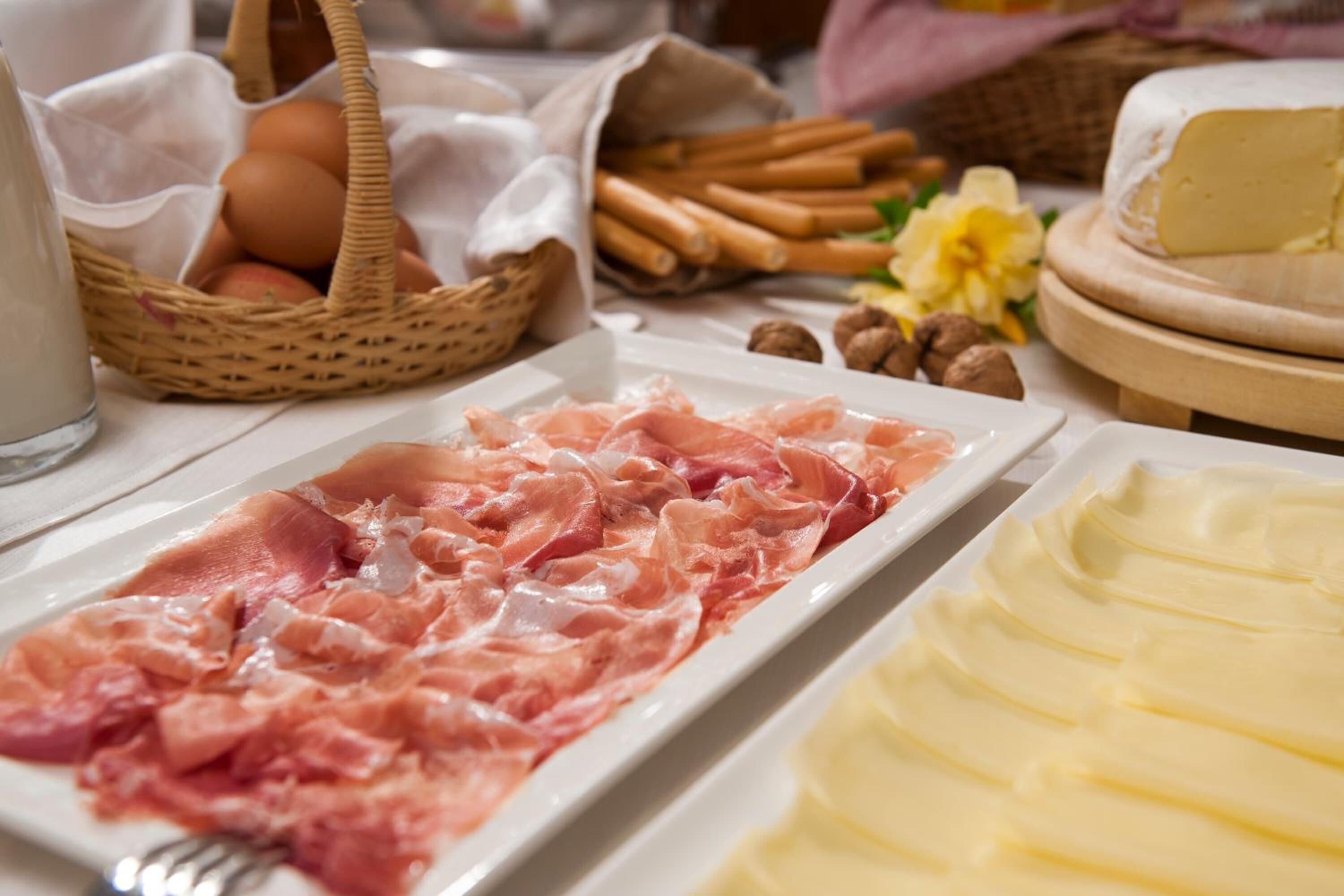A table with various food items including sliced meats, cheese, and eggs.