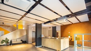 Un espace d’accueil moderne avec un comptoir d’accueil en bois, un escalier et une plante en pot.