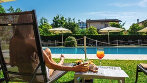 Un espace aménagé au bord de la piscine, avec une table, des chaises et des parasols.