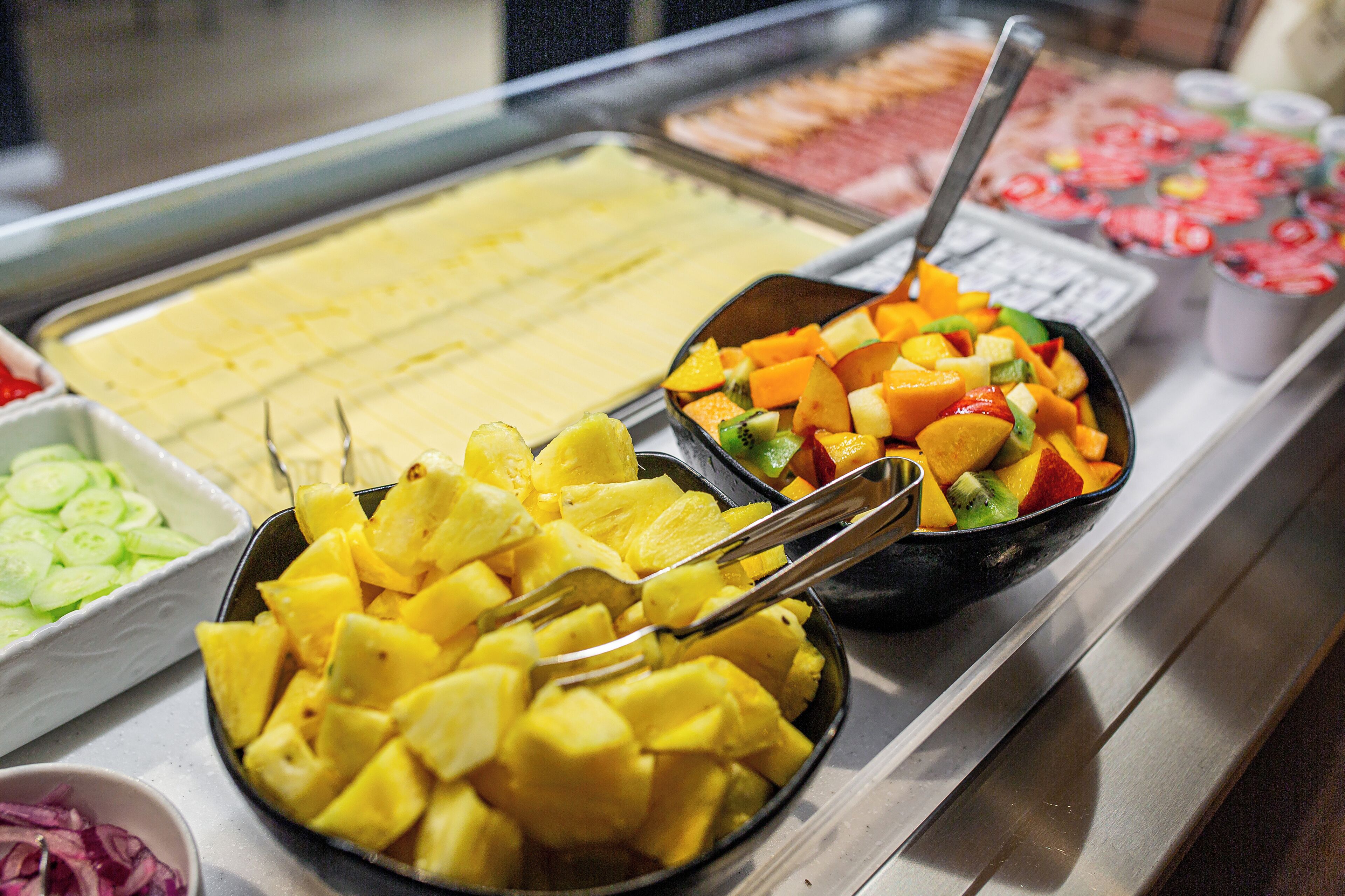 Ein Buffet mit verschiedenen Früchten und Gemüsesorten, darunter Ananas, Kiwi und Melone.