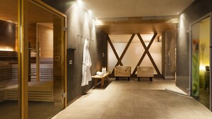 A modern spa room with a wooden bench, a towel rack, and a bench with a towel. - Hotel Heubad (Fie allo Sciliar)