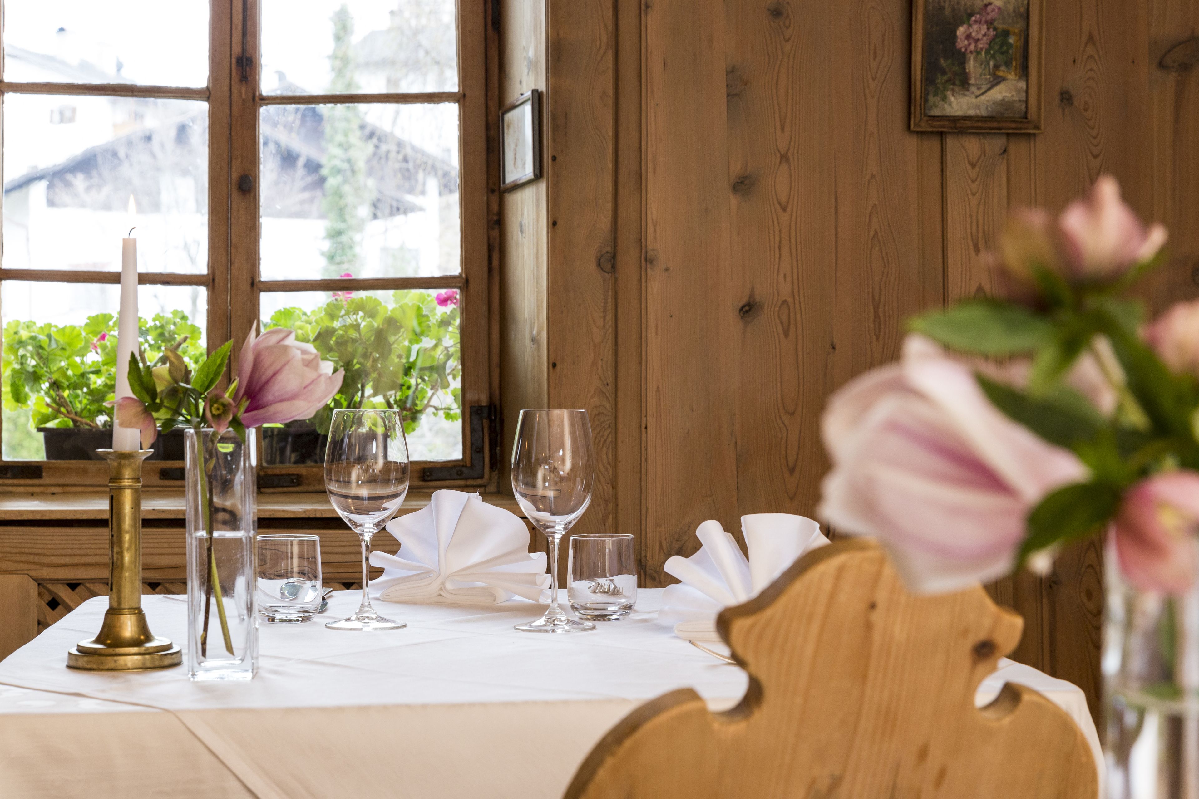 A dining table set with white tablecloth, clear glassware, and a candle holder.