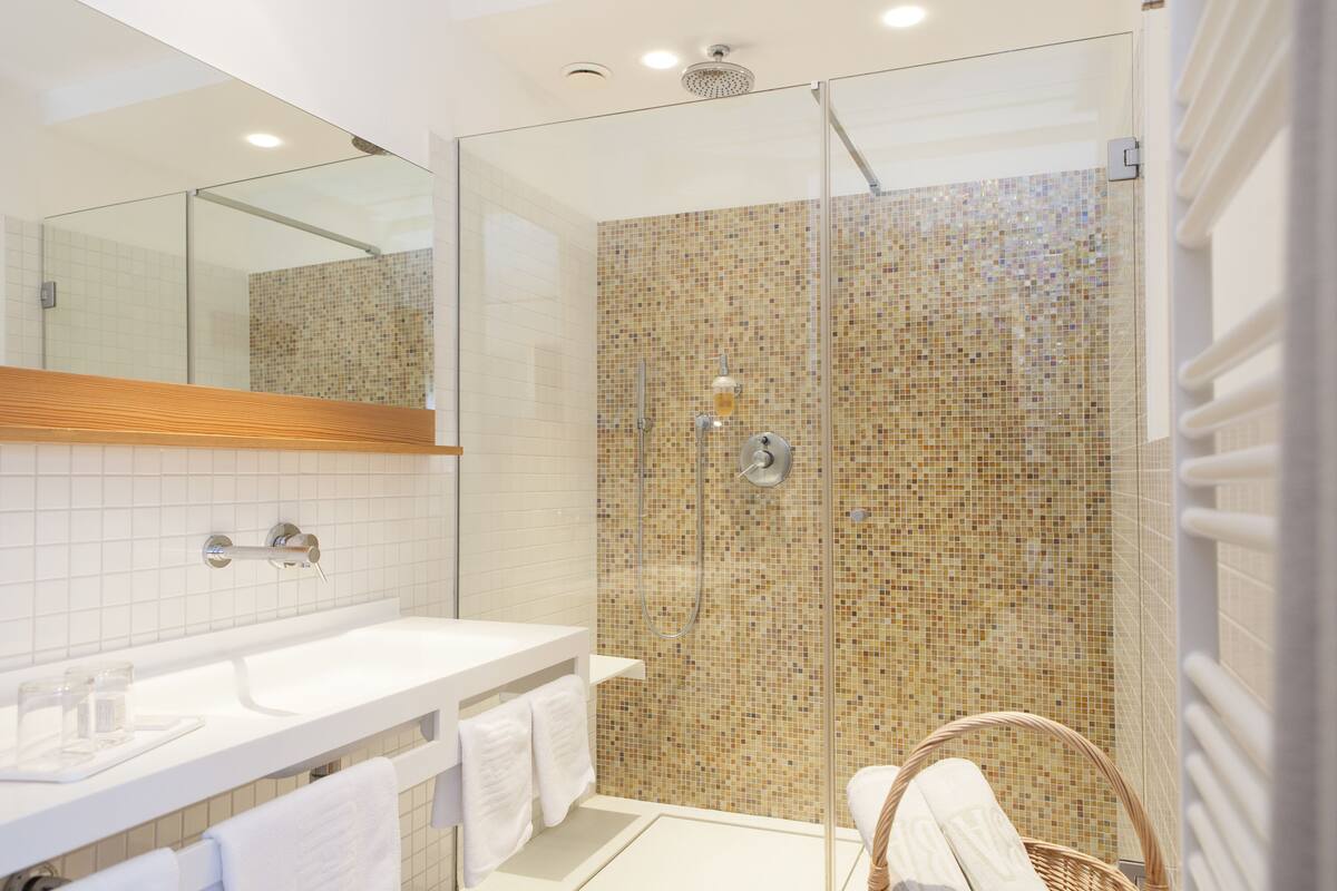 Une salle de bain moderne avec une douche à parois de verre, un lavabo blanc et un miroir au-dessus.