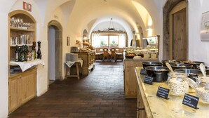 A bakery with a rustic interior, featuring wooden shelves with baked goods, a brick floor, and arched ceilings. - Hotel Heubad (Fie allo Sciliar)