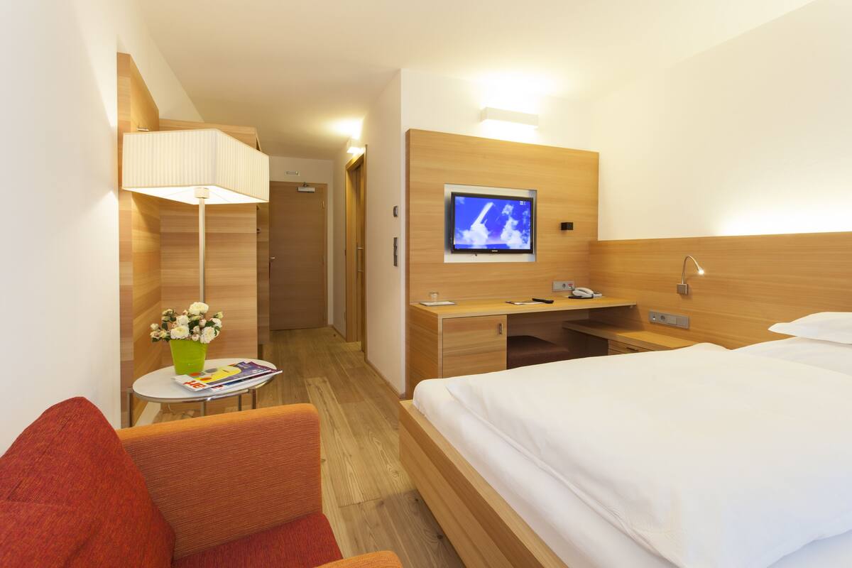 Une chambre d’hôtel avec un lit, un bureau, une chaise, une télévision et une lampe.