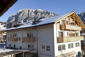 Un bâtiment à deux étages, doté de balcons, portant l’inscription « Café-restaurant », se dressant sur un fond de montagnes.