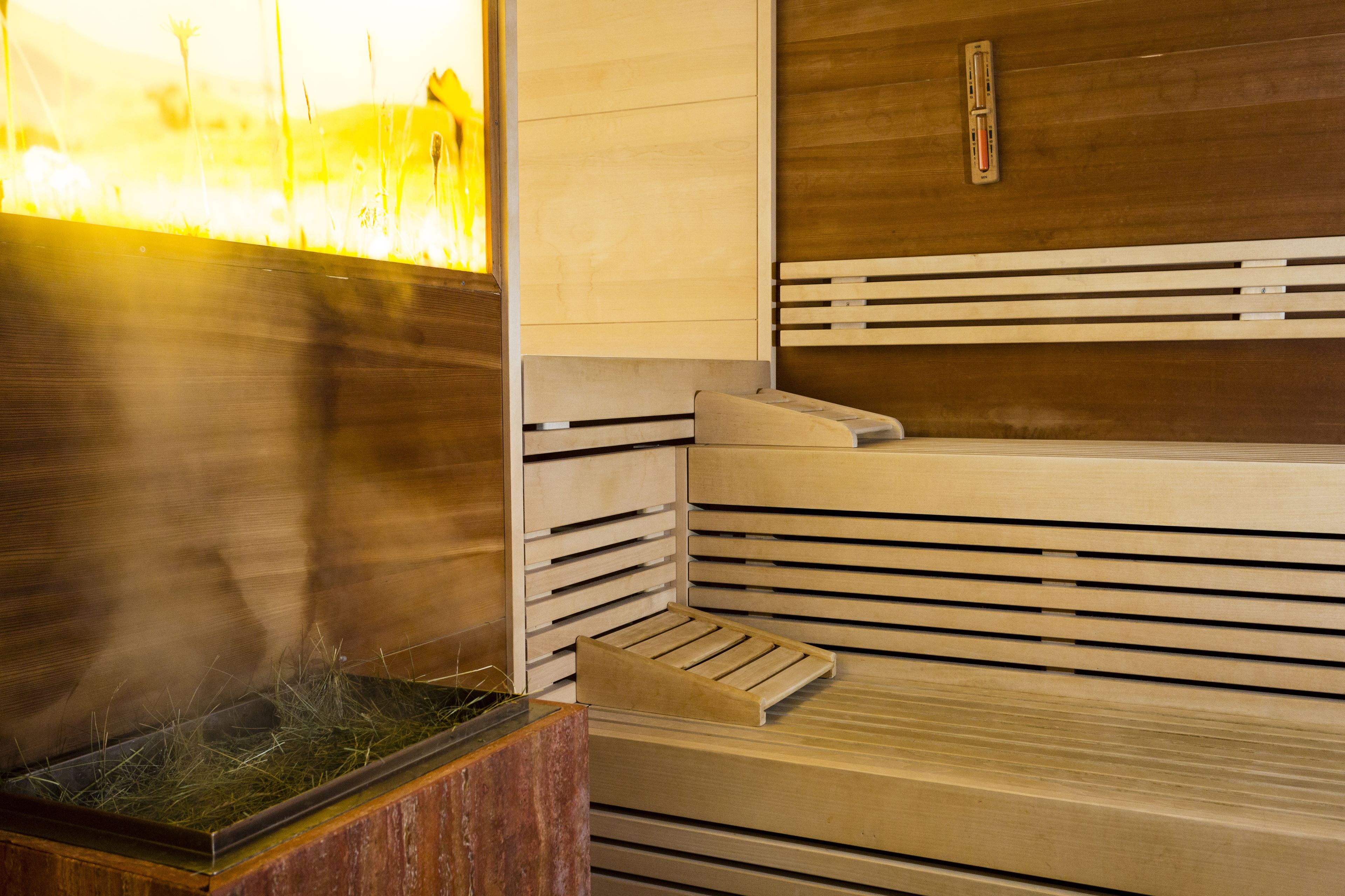 A sauna with a wooden bench and a glass enclosure.
