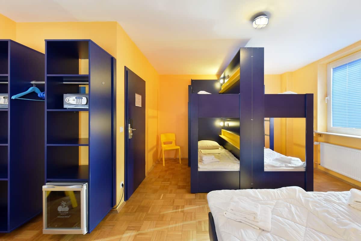 A room with bunk beds, a wardrobe, and a small table.