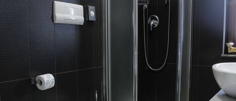 Et moderne badeværelse med bruseniche, bidet, toilet og håndvask.